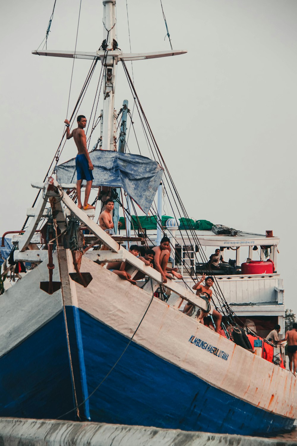 femme en veste en jean bleu et jean bleu assis sur le bateau bleu et blanc pendant