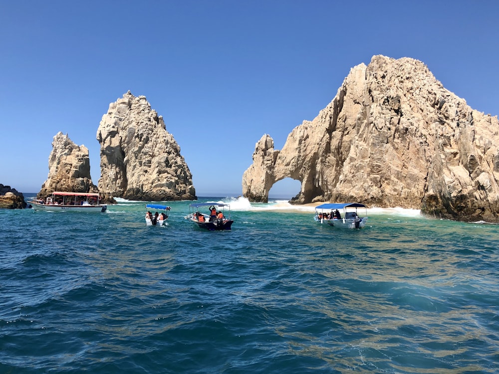 people in blue water near brown rock formation during daytime