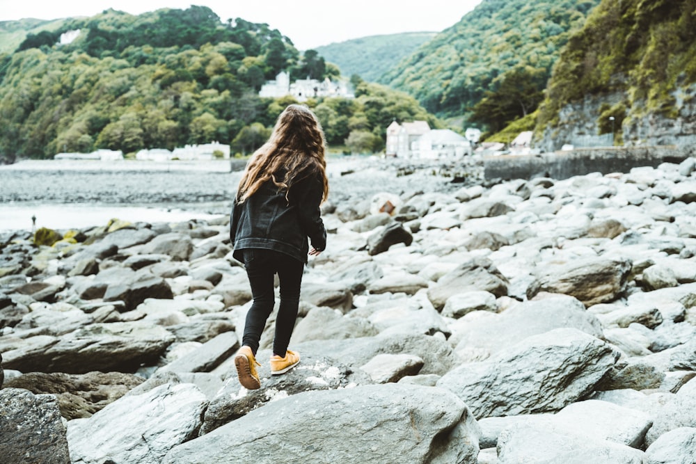 Femme en veste noire debout sur Rocky River pendant la journée