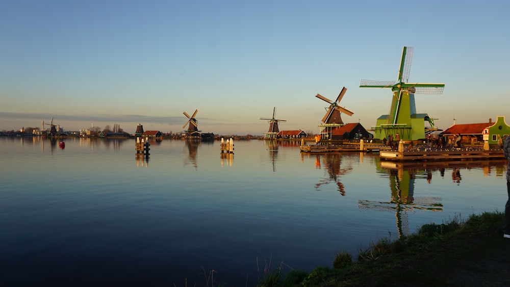 brown wooden windmill on green grass field near body of water during daytime