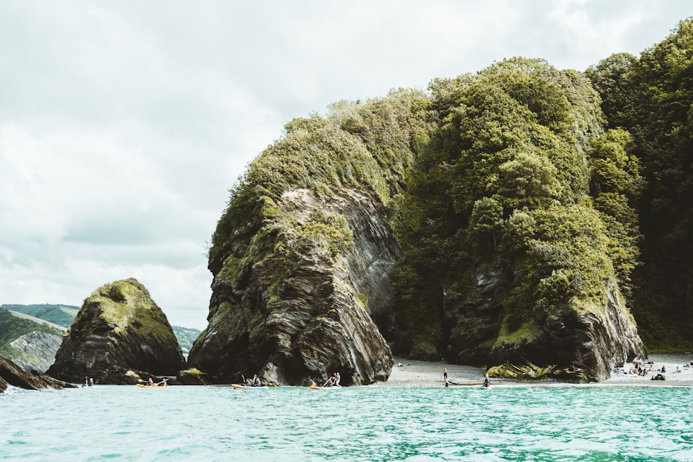 formazione rocciosa verde e grigia sullo specchio d'acqua durante il giorno