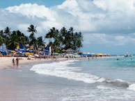 A panoramic shot of the beach filled with colorful tents, VIP lounges, and lively crowds.