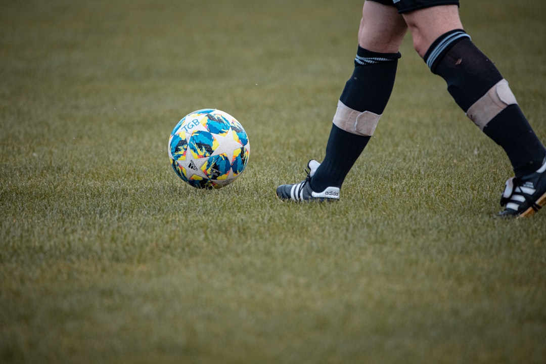 person in black and white nike soccer shoes standing on green grass field during daytime