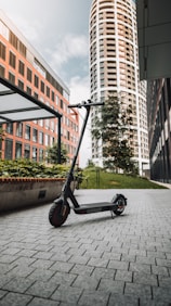 black and gray kick scooter on gray concrete pavement near brown concrete building during daytime