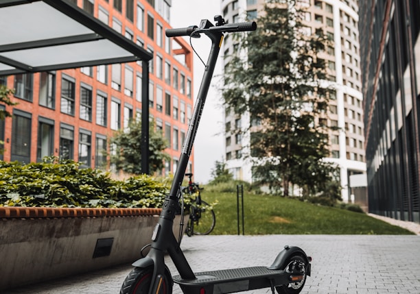 black and gray kick scooter on gray concrete pavement near brown concrete building during daytime