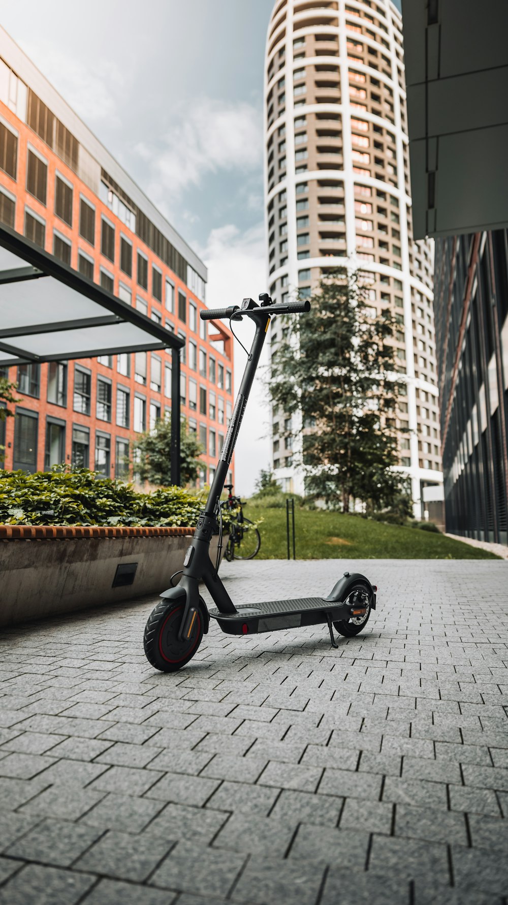 trottinette noire et grise sur le trottoir en béton gris près d’un bâtiment en béton brun pendant la journée