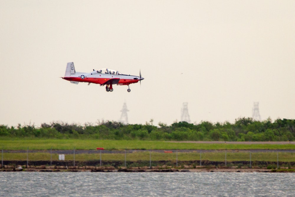 white and red airplane flying over the sea during daytime