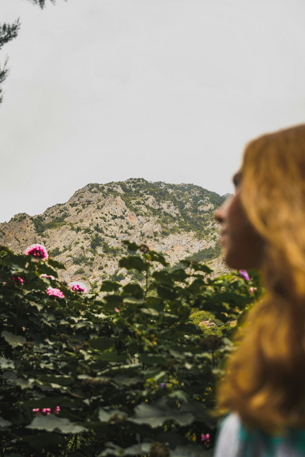 woman in brown jacket standing near green plants during daytime