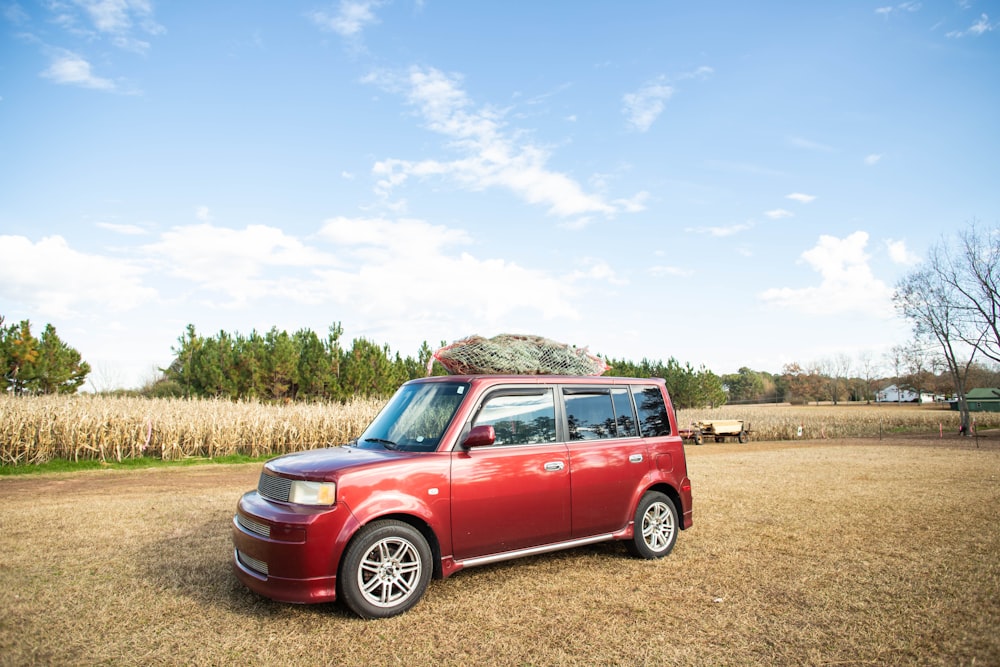 red suv on brown field under blue sky during daytime