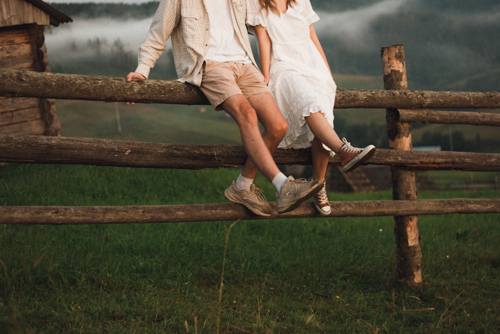 woman in white dress shirt sitting on brown wooden fence