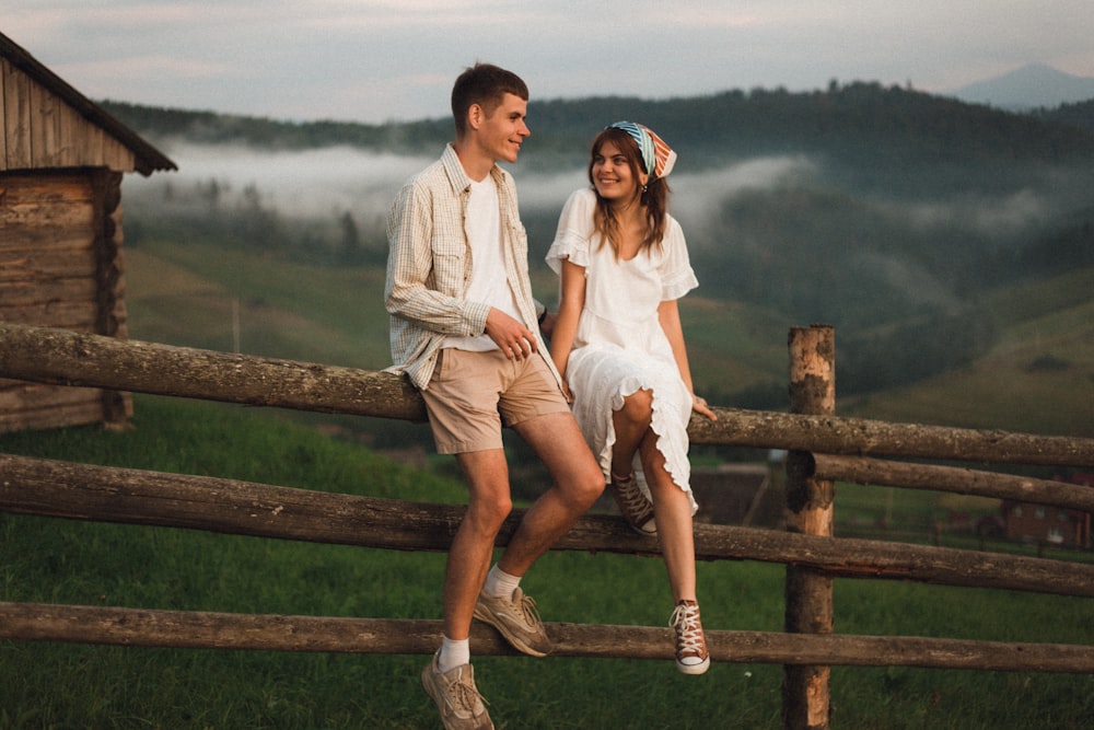 man and woman sitting on brown wooden fence during daytime