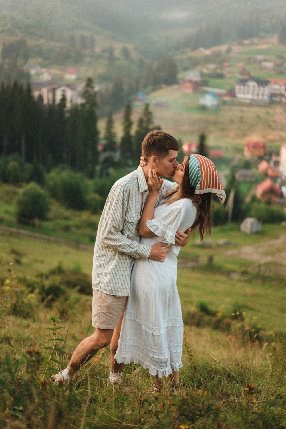 uomo in camicia bianca che bacia la donna in abito bianco sul campo di erba verde durante il giorno