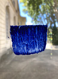 Professional painter applying deep blue paint to a commercial building exterior on a sunny day.