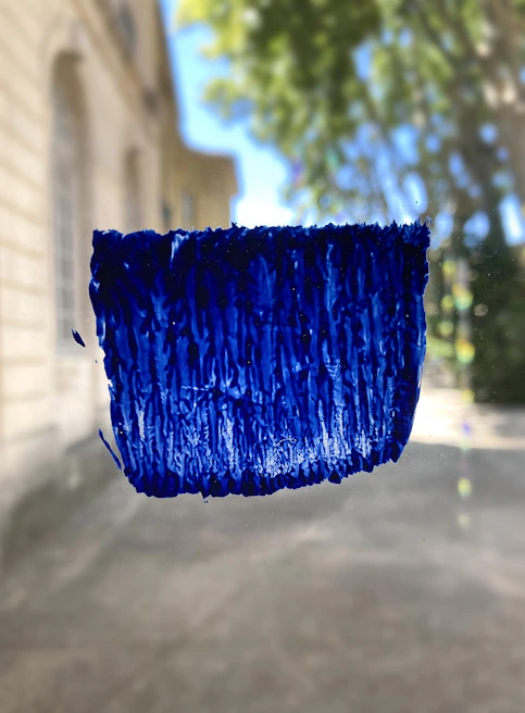 Close-up of a painter applying a vibrant blue coat on a commercial facade