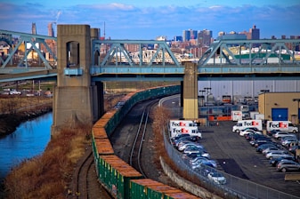 A freight vehicle crossing a busy interstate with city skyline in the background