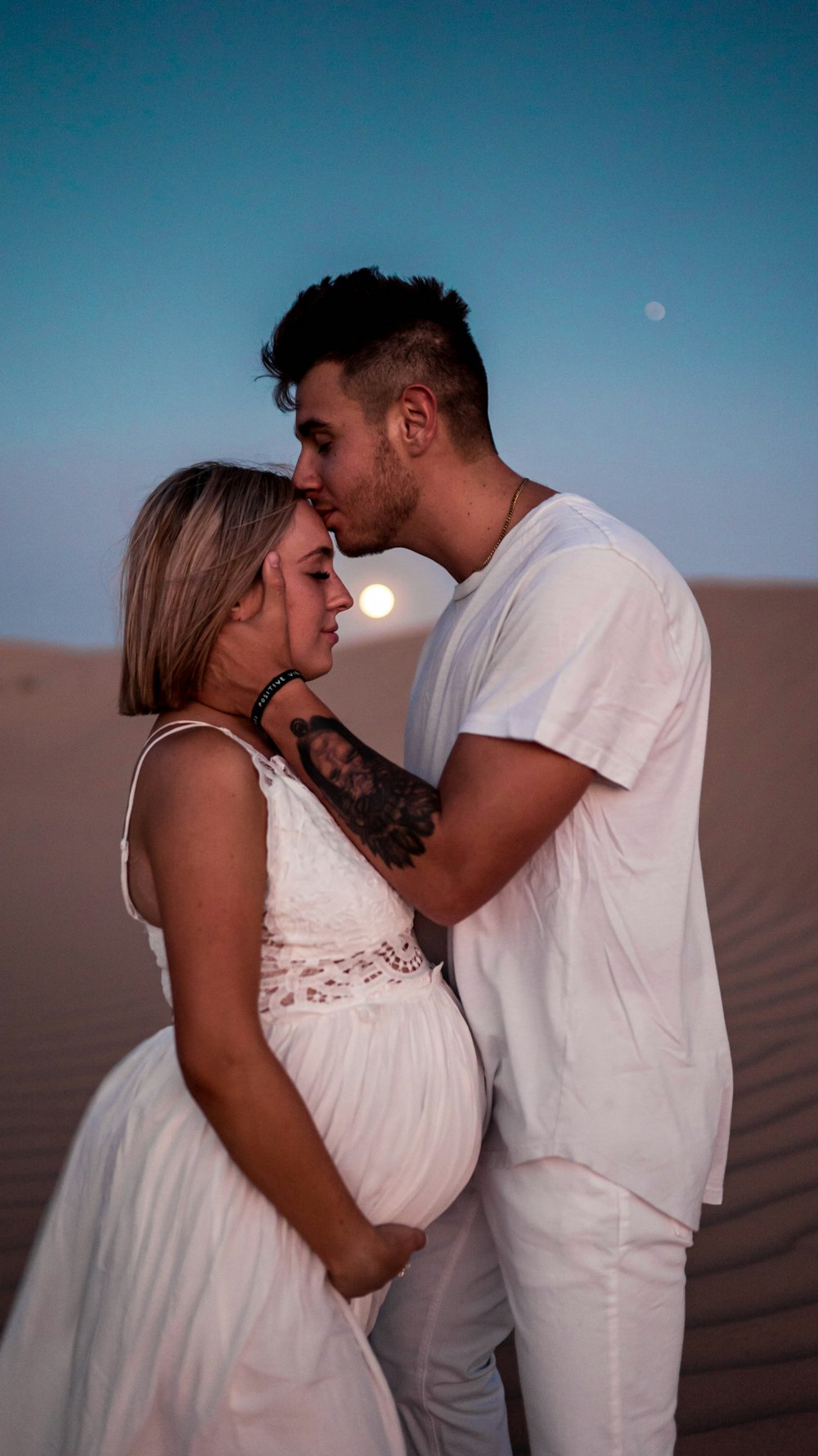 man in white t-shirt kissing woman in white sleeveless dress