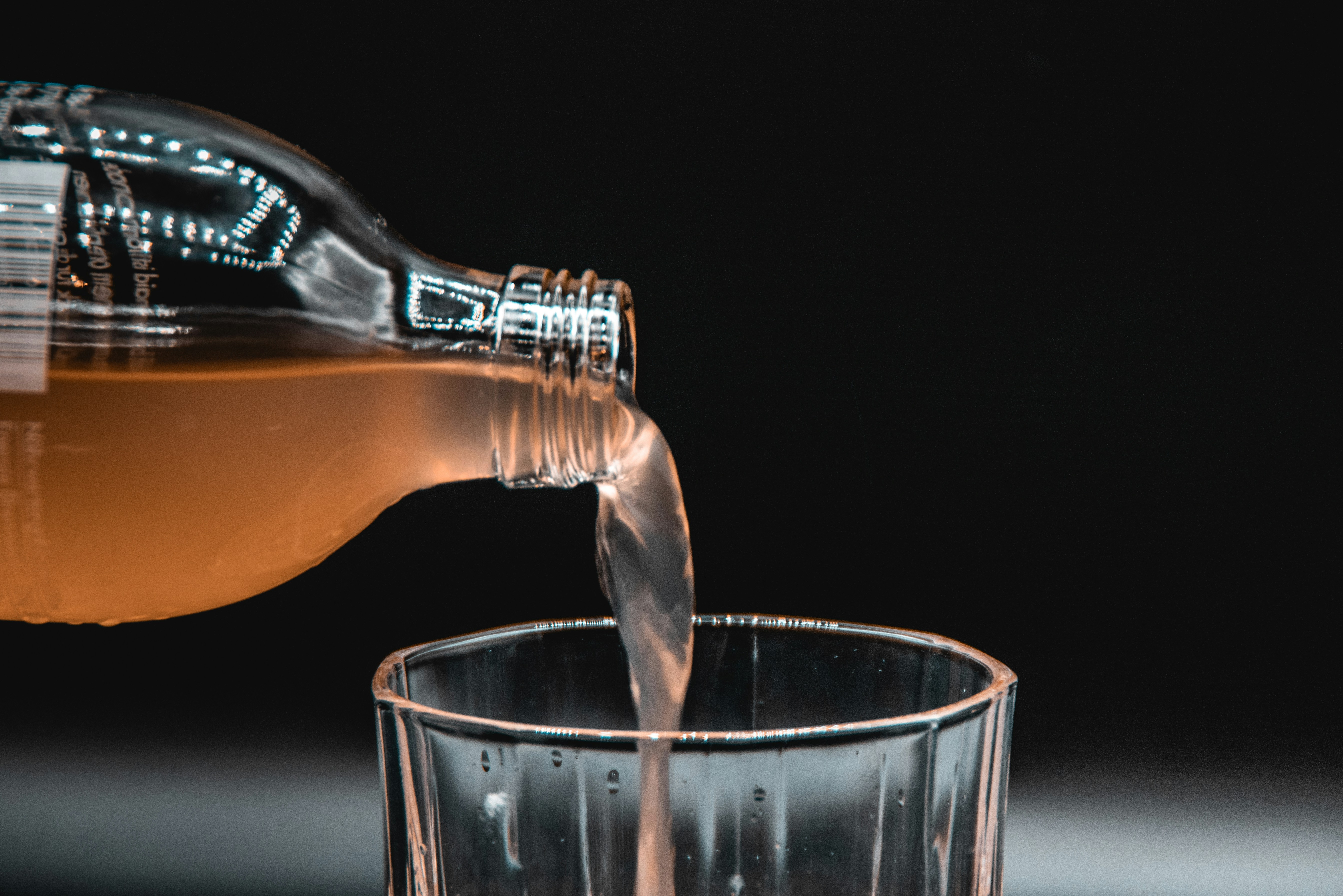 person pouring water on clear drinking glass