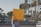 A person stands on a street holding a bright yellow sign that reads 'WHAT IF IT WAS YOUR CHILD? #SavetheChildren'. The background shows a typical urban setting with palm trees, cars, and traffic signals.