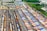 Aerial view of a large cargo terminal filled with colorful shipping containers organized in rows. Railway tracks are visible, some with train cars loaded with containers. The area is surrounded by industrial buildings and greenery.