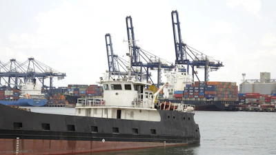 Wide shot of multiple ship unloaders working simultaneously at a bustling industrial port.