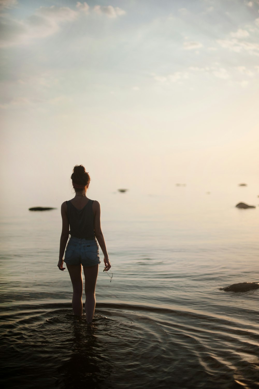 woman in black tank top and white shorts walking on beach during daytime