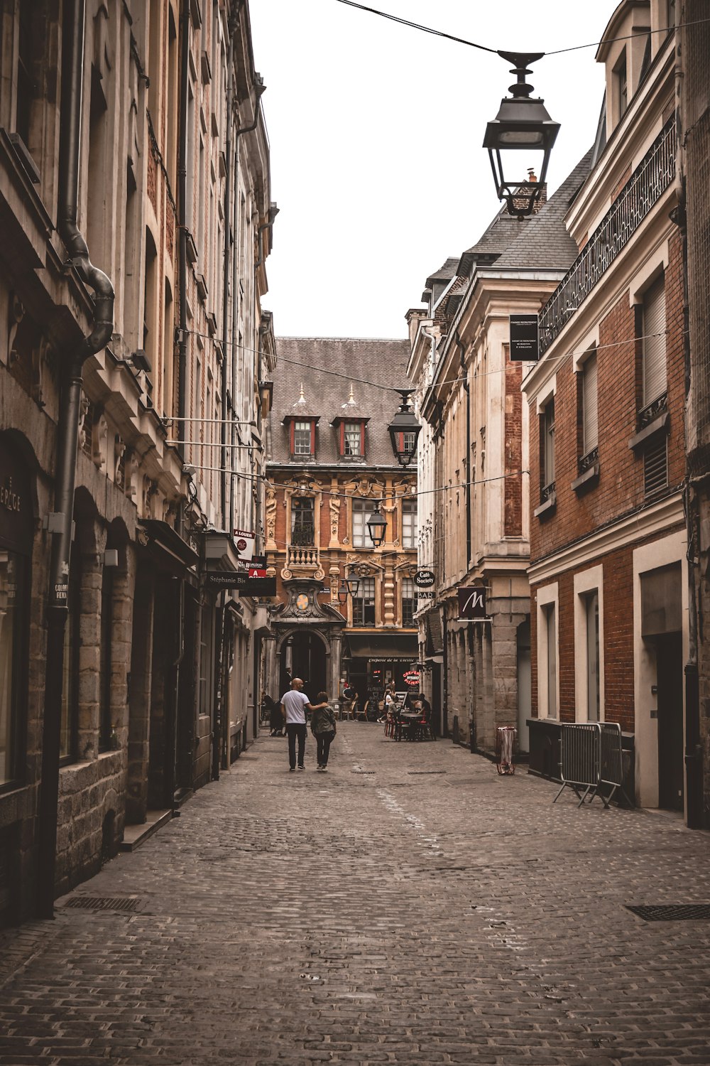 people walking on street between brown concrete buildings during daytime