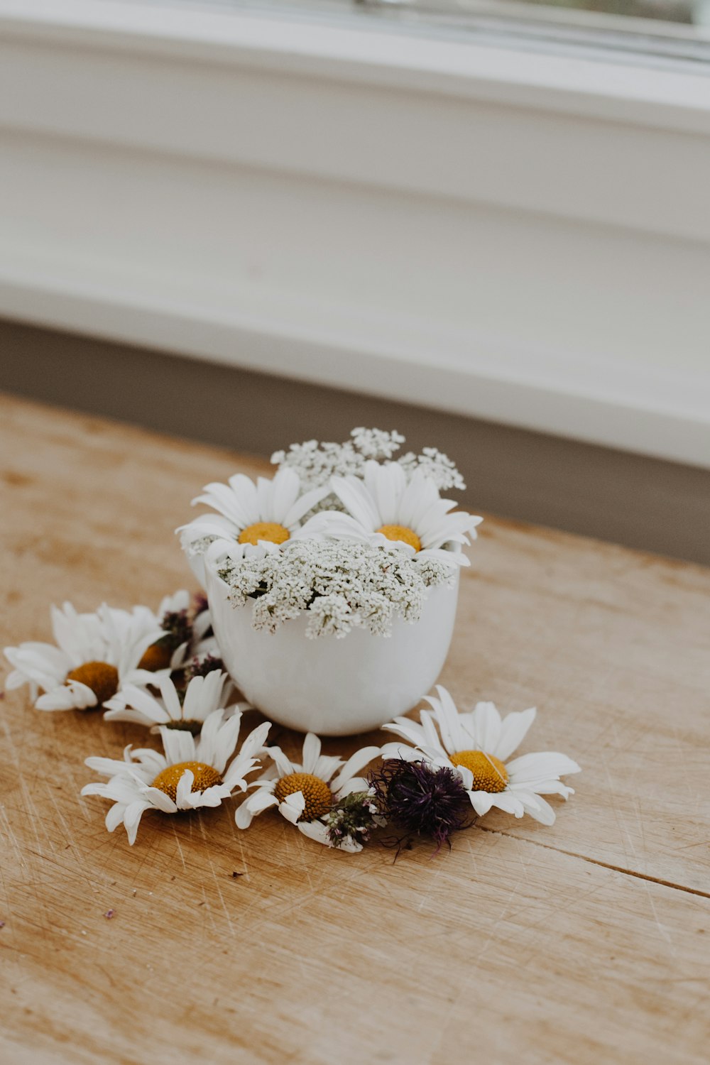 white and yellow flowers on white ceramic vase