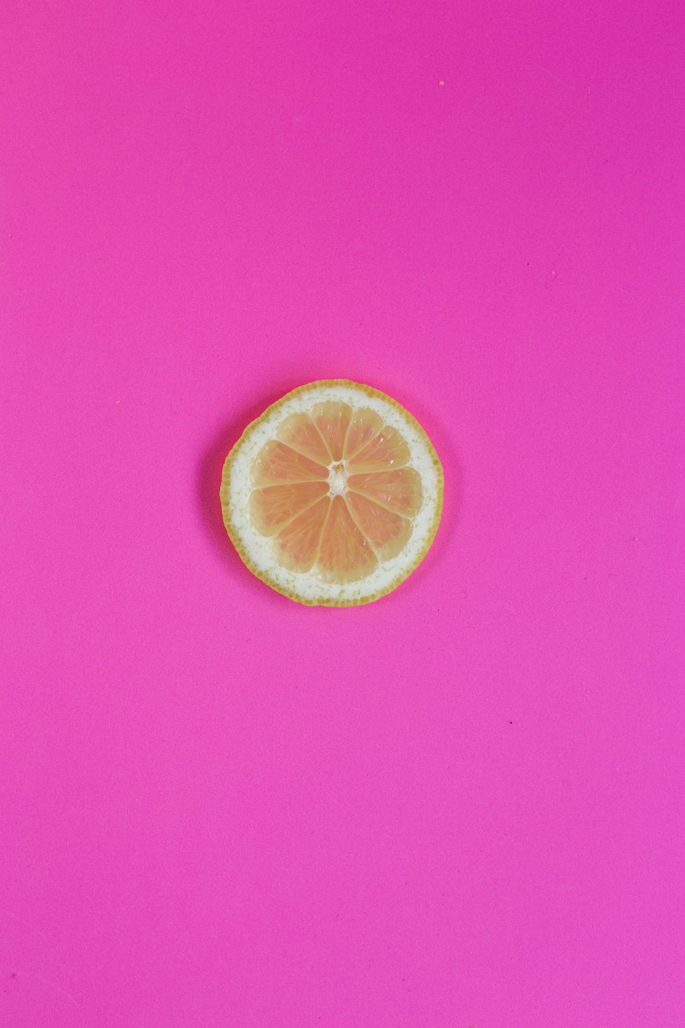 sliced orange fruit on pink surface