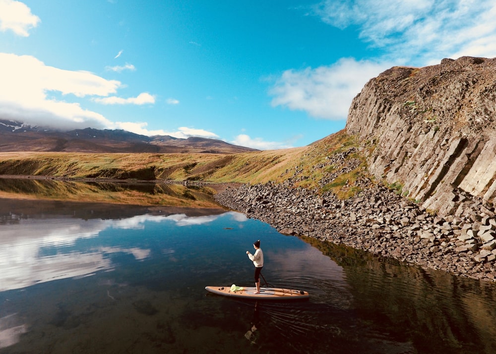 woman in white shirt sitting on brown wooden boat on river during daytime