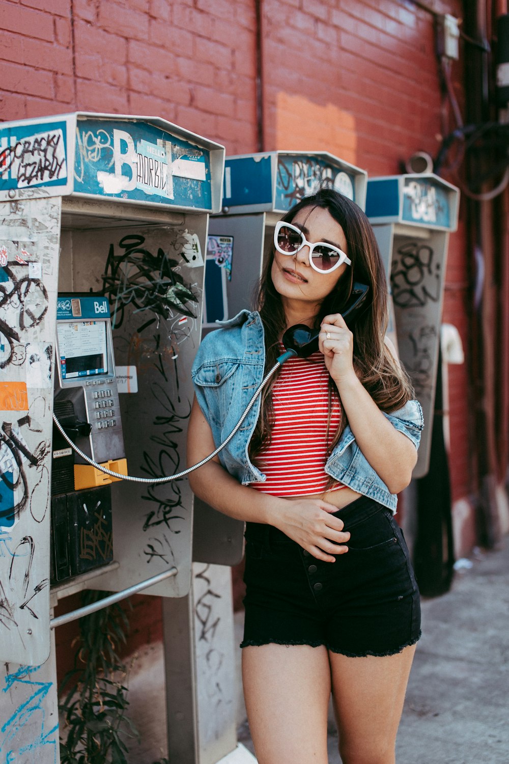 woman in blue and white striped shirt and black skirt wearing sunglasses