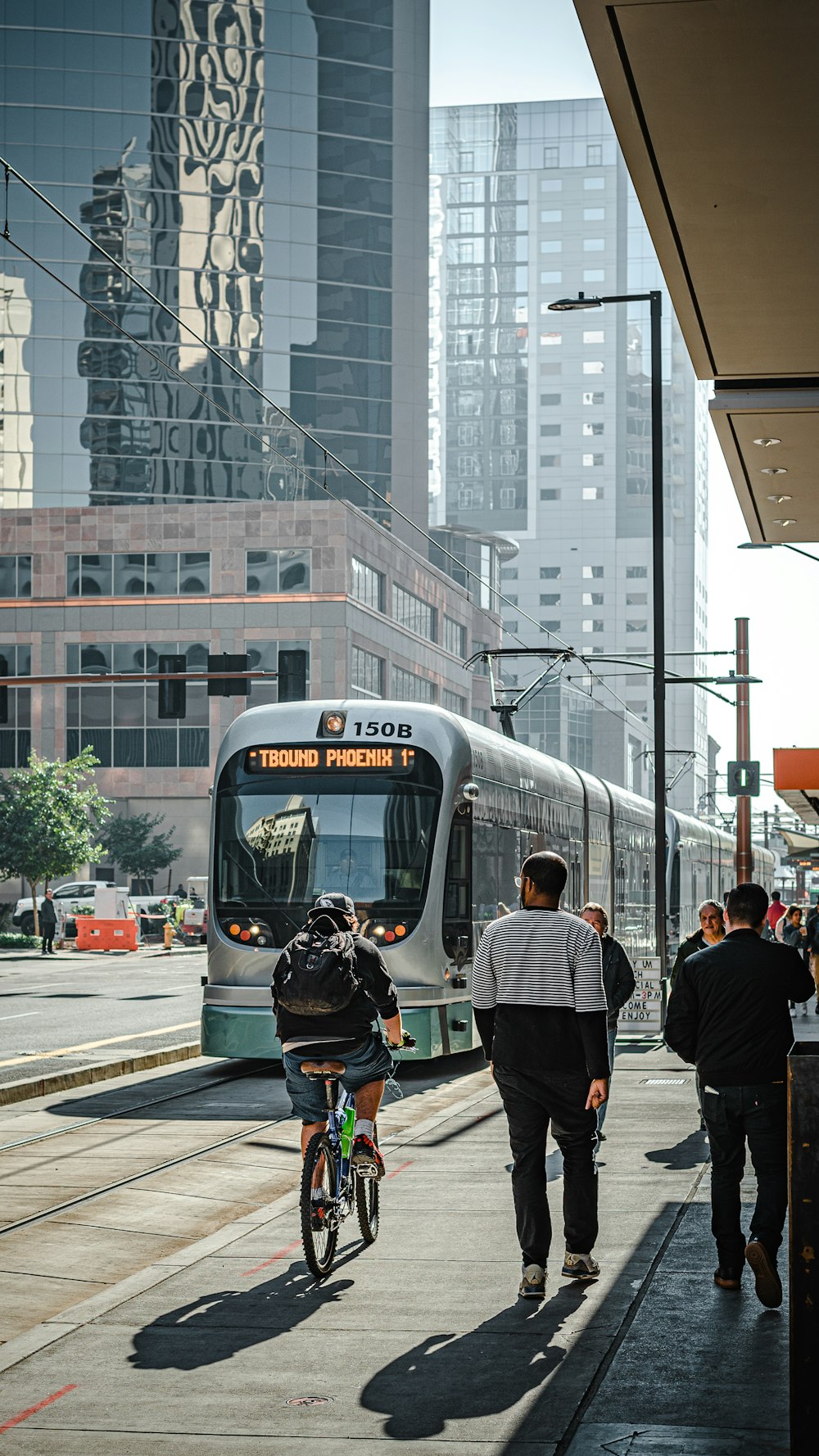 昼間、白と赤の電車の近くの歩行者専用車線を歩く人々