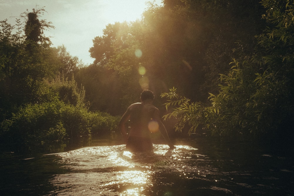 hombre en pantalones cortos negros de pie en el río durante el día