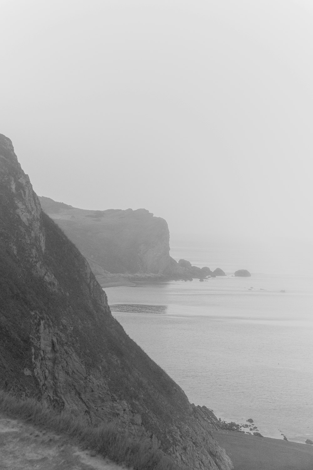 grayscale photo of rock formation on sea