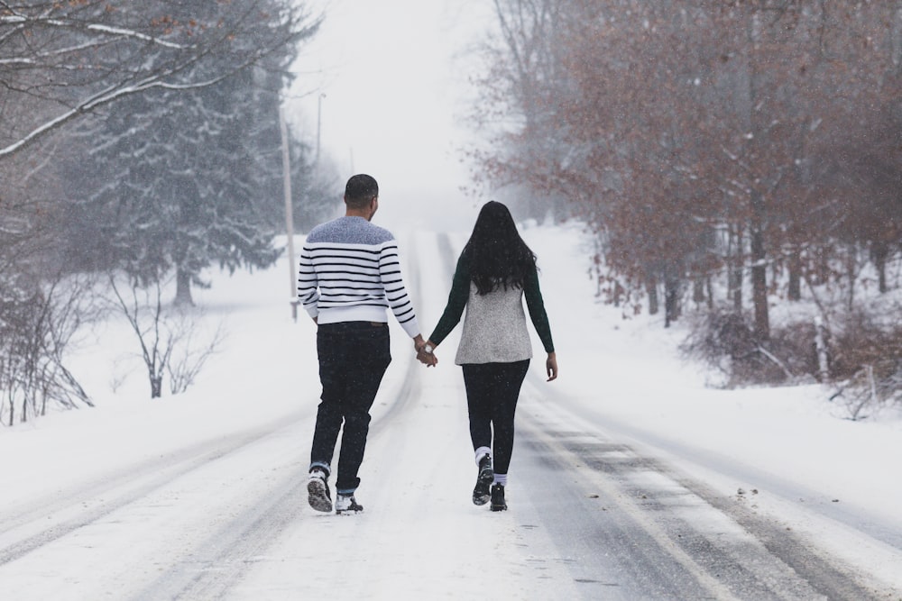 woman in white and black striped long sleeve shirt and black pants walking on snow covered