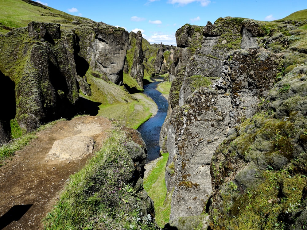 green grass and gray rocky mountain beside river during daytime