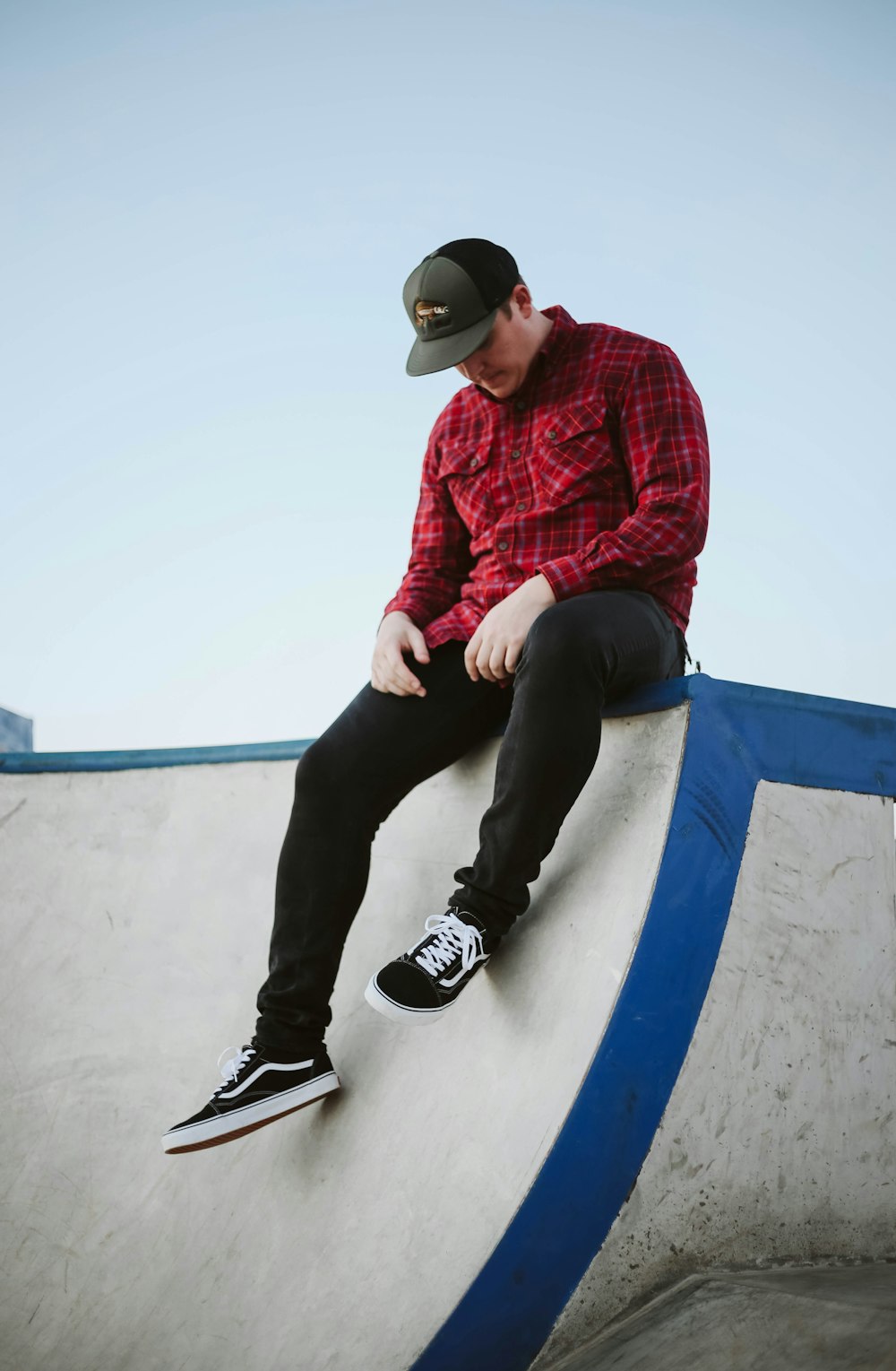 man in red and blue plaid dress shirt and black pants sitting on white and blue