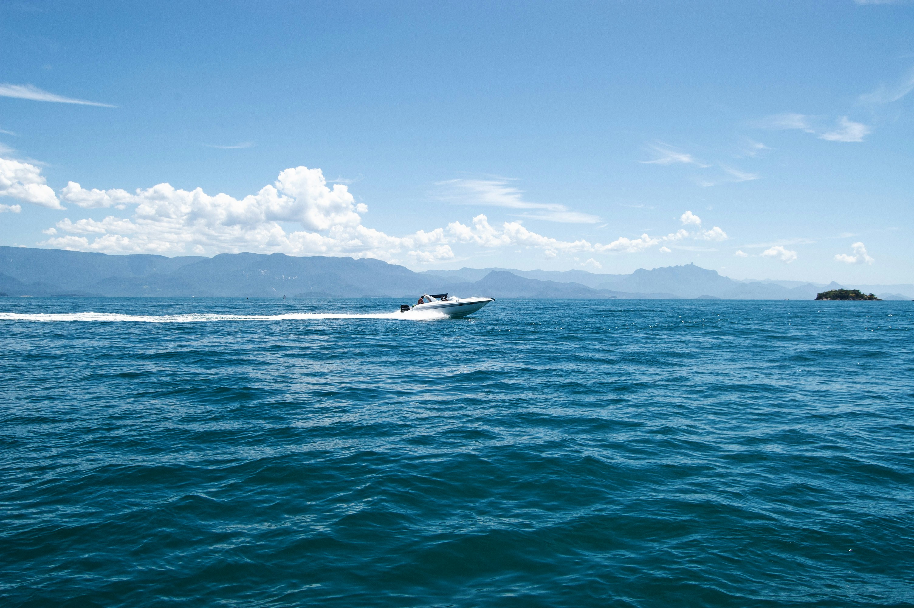 white and black boat on sea under blue sky during daytime, [pt-br] Lancha em mar aberto.</p><p>[en-us] Motorboat on open sea.