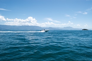 white and black boat on sea under blue sky during daytime