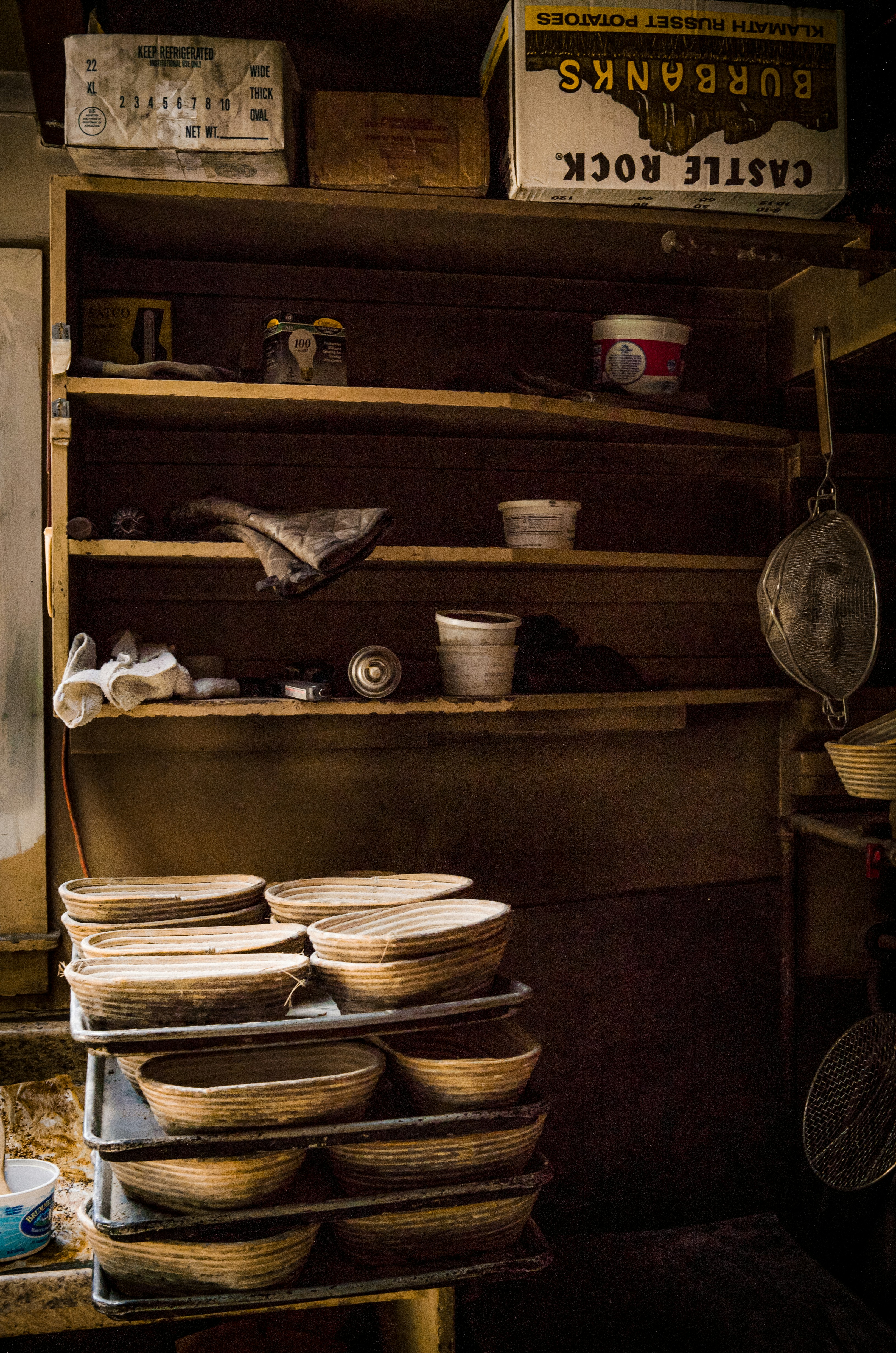 Dim, cluttered pantry with overstuffed shelves, mismatched containers, and items falling over in low light