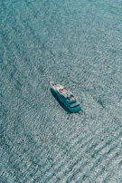An editorial-style shot of a yacht cutting through deep blue waters with a distant island horizon.