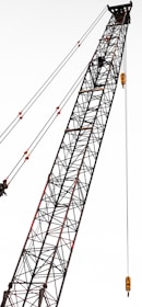 A tall construction crane with a lattice structure, stretching diagonally across the frame. The crane is equipped with several pulleys and cables, showcasing its industrial design.