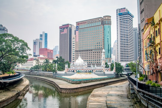 white and blue boat on river near city buildings during daytime in Jamek Mosque of Kuala Lumpur Malaysia