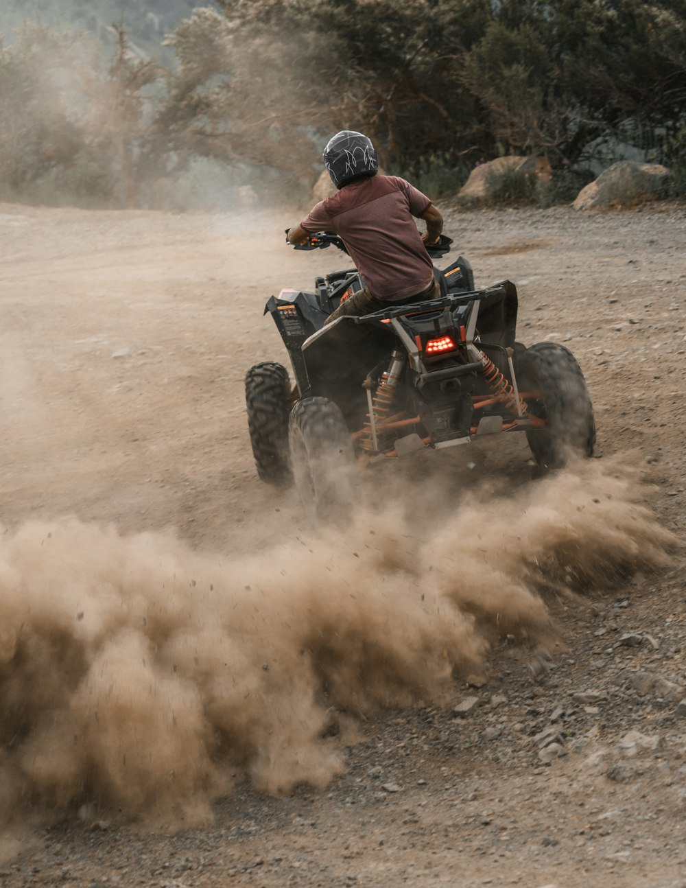 man riding atv on dirt road during daytime