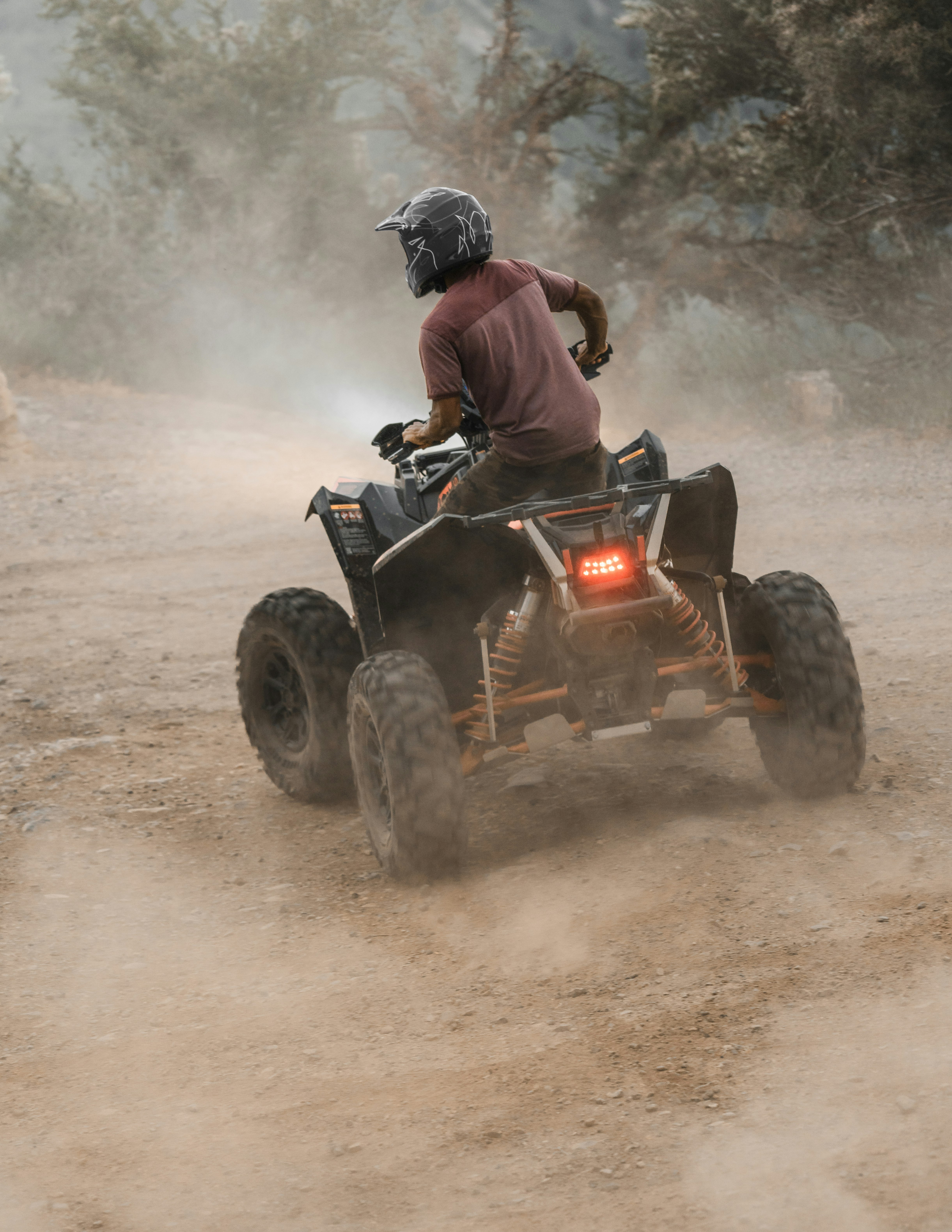 man riding atv on dirt road during daytime