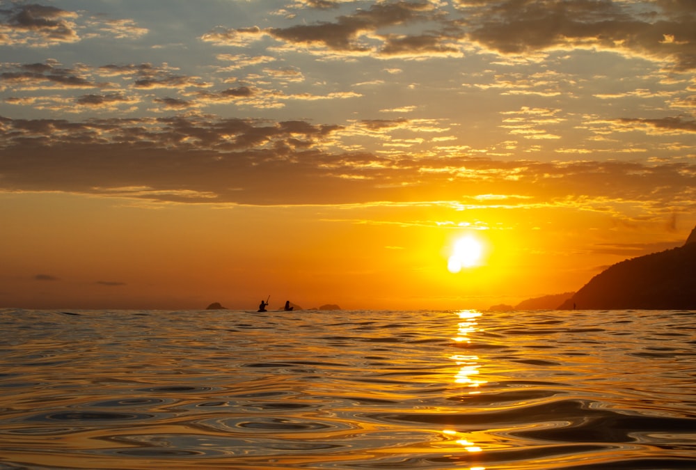 silhouette of people on sea during sunset