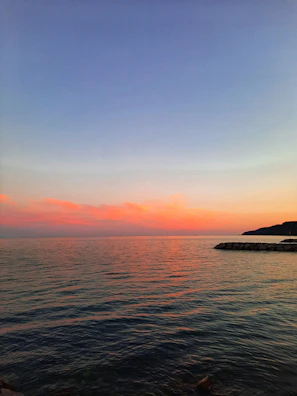 A tranquil seaside view at sunset with layered textures and earthy tones.