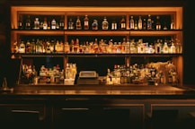 A stylish bar with shelves of fine wine bottles and soft red lighting.