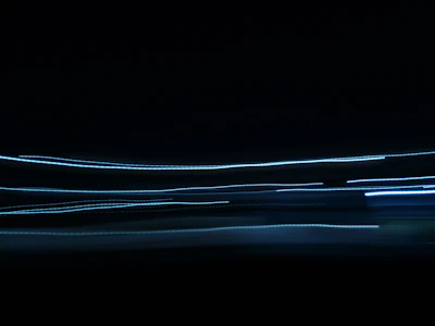 Abstract light trails symbolizing connection and conversation in a dark room.