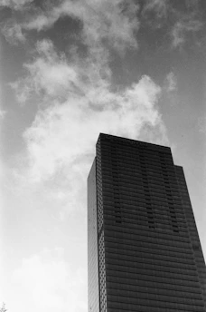 A stark black-and-white photo of a courthouse facade with tall pillars and a cloudy sky overhead.