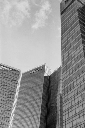 Tall modern office buildings with glass facades extend into the sky. The word 'Ascott' is prominently displayed on one of the buildings. The sky is overcast, giving the scene a subdued atmosphere.